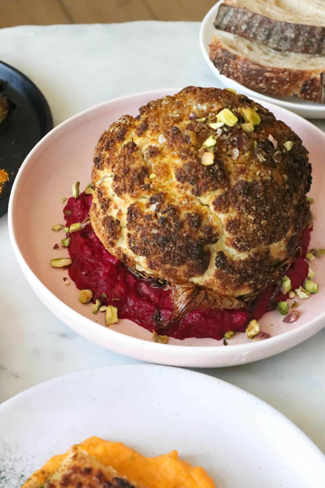 Whole heirloom cauliflower wood-roasted to charred edges, served on beetroot purée with pistachio.