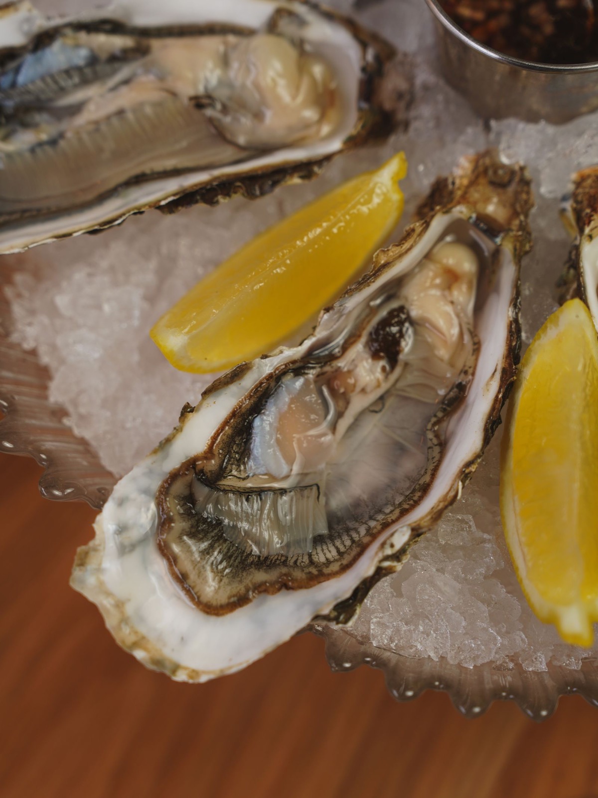 Freshly shucked oysters on the half shell with lemon wedges on crushed ice.